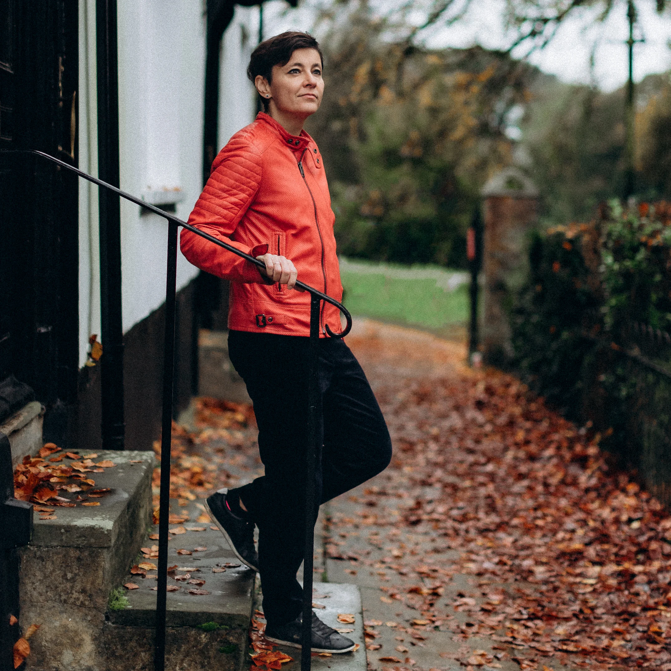 Irina Dmitrieva walking down outdoor stone steps, photographed from behind, surrounded by autumn foliage.