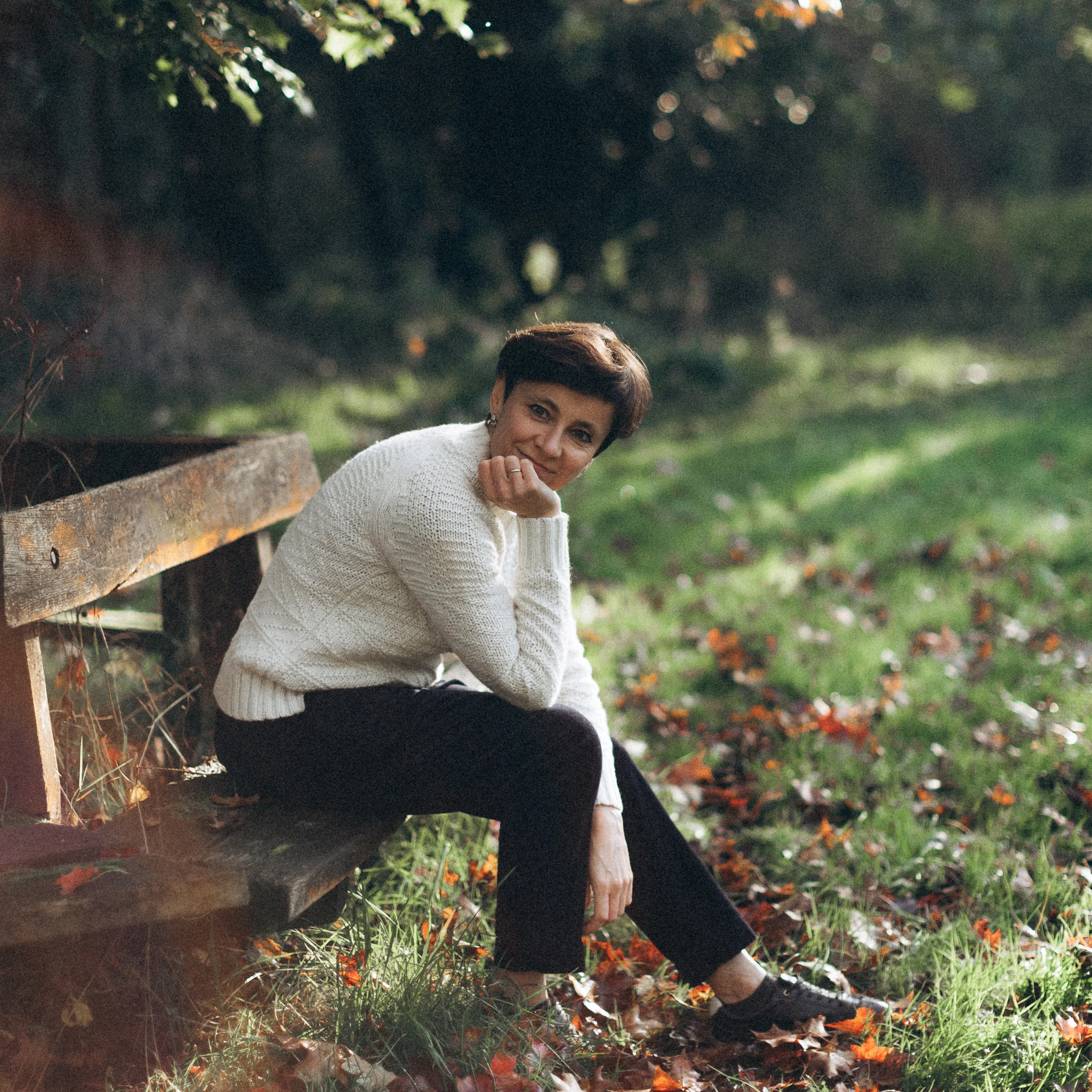 Irina Dmitrieva sitting outdoors on grass, relaxed and smiling, wearing casual clothing.