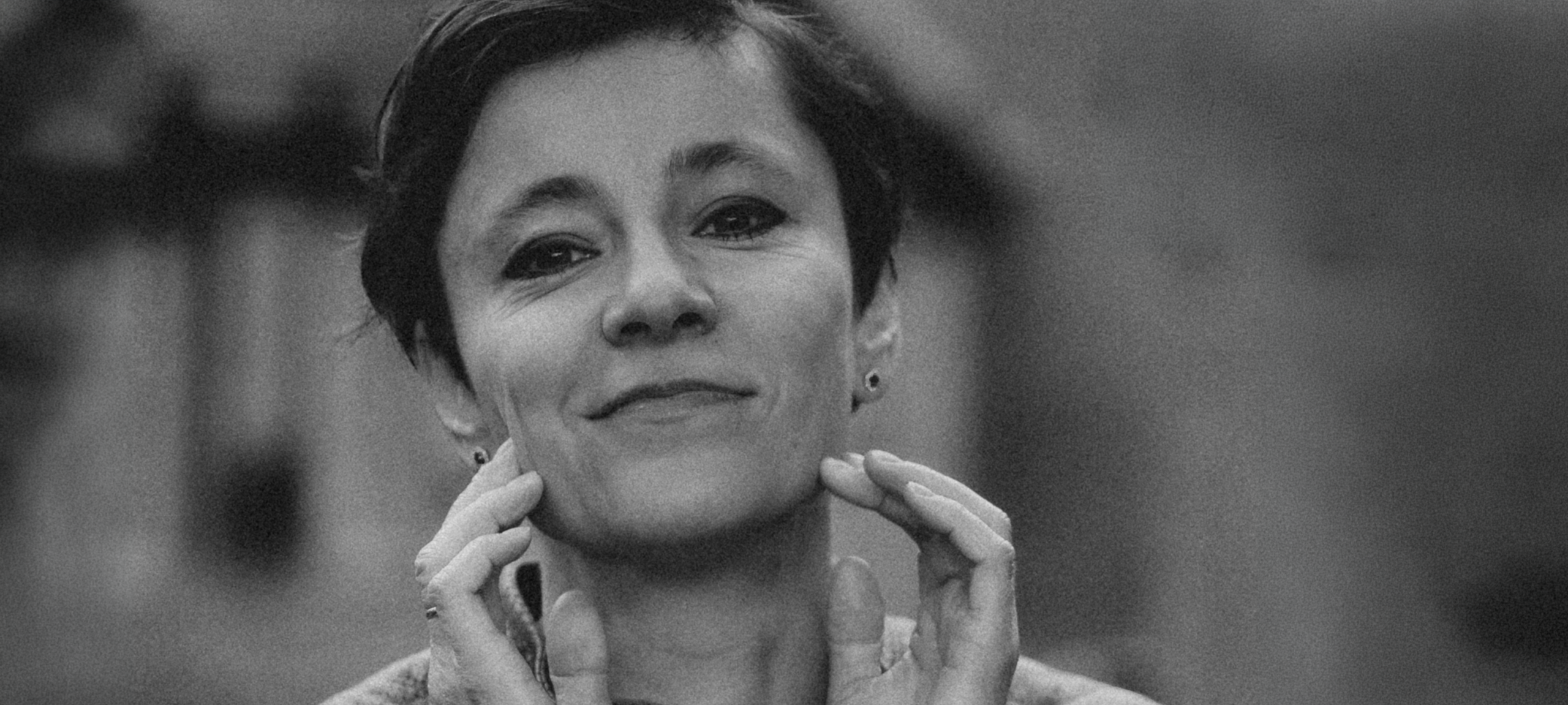 Black and white portrait of Irina Dmitrieva resting her chin on her hand, looking directly at the camera with a calm and open expression.