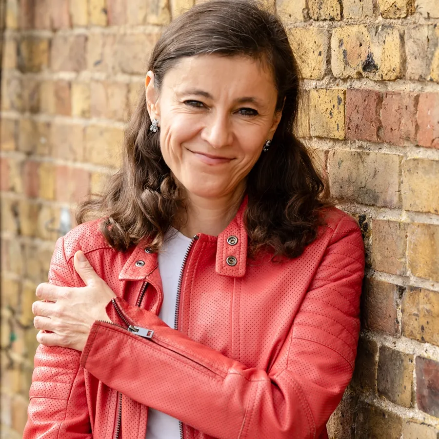 Irina Dmitrieva smiling beside a brick wall