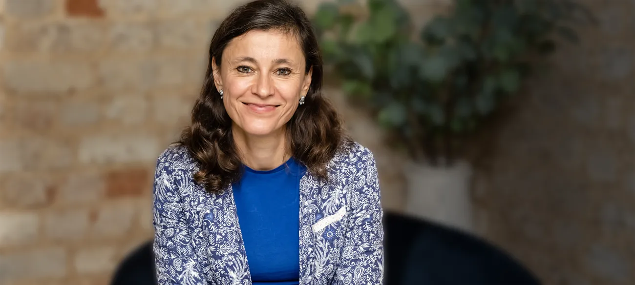 Irina Dmitrieva seated and smiling in a relaxed portrait